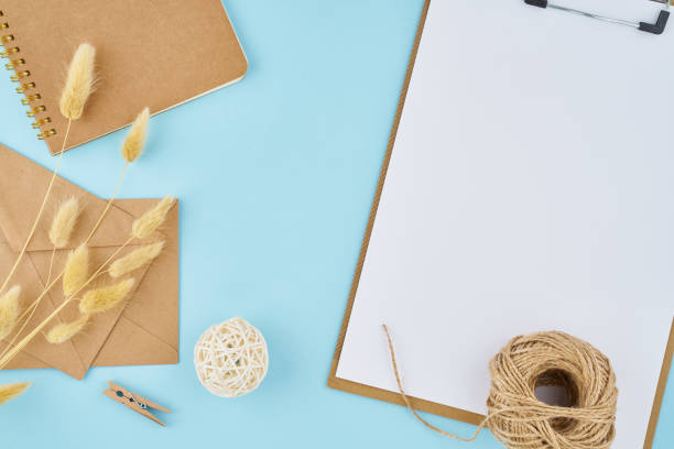 istock Zero waste concept. White sheet on clipboard, craft envelopes on a bright blue office modern desktop. Environmentally friendly and natural 1190541982