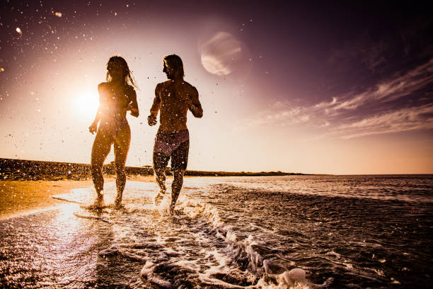 istock Young couple running on the beach at sunrise. 1190547023
