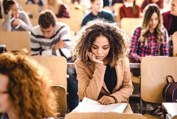 istock Young university student reading textbook on a class at lecture hall. 1190547724
