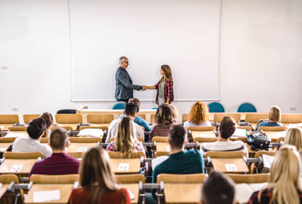istock Happy professor and college student shaking hands in front of whiteboard. 1190548794