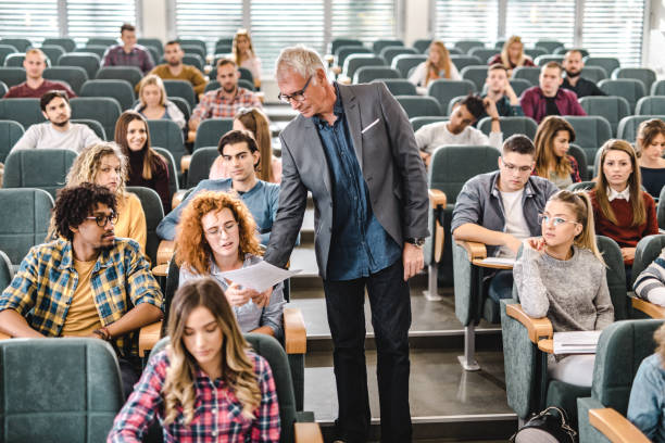 istock Senior professor assisting his students on a class at lecture hall. 1190548810