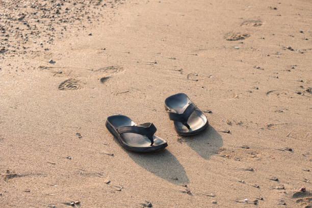 istock Black pair of flip flops on the beach 1190549769