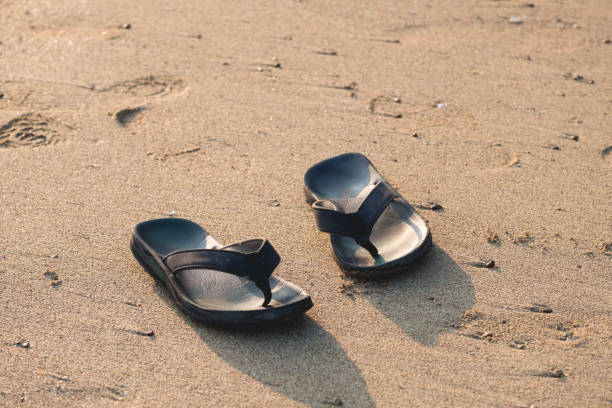 istock Black pair of flip flops on the beach 1190549775