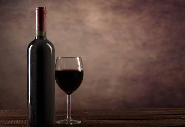 istock Red Wine in glass and bottle with dust on a dark background with copy space 1190554461