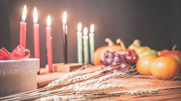 Kwanzaa holiday concept with decorate seven candles red, black and green, gift box, pumpkin,corn and fruit on wooden desk and background. Kwanzaa holiday concept with decorate seven candles red, black and green, gift box, pumpkin,corn and fruit on wooden desk and background. angolan kwanza photos stock pictures, royalty-free photos & images