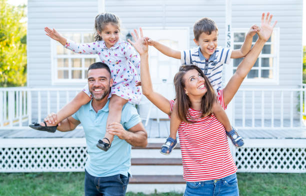 istock Parents having fun in front yard carrying children piggyback 1190560726