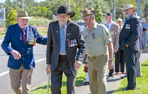 An old national serviceman wearing a suit and black cowboy hat is assisted by his ex-military friends during preparations for ANZAC Day parade in Cooroy, Queensland.
