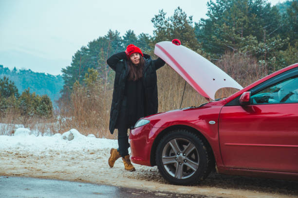 istock woman looking at engine broken car at winter road side 1190566993