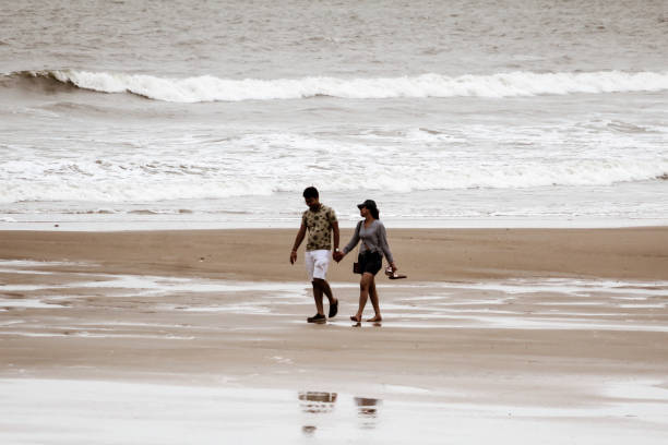 젊은 귀여운 부부는 일몰에 해변에서 산책. 배경에 바다 파도의 아름다운 황혼 의 분위기. 저조도 및 움직임으로 인해 두 사람이 흐림을 합니다. 공간을 복사합니다. 고아, 인도 여행 - holding hands honeymoon dating flirting 뉴스 사진 이미지