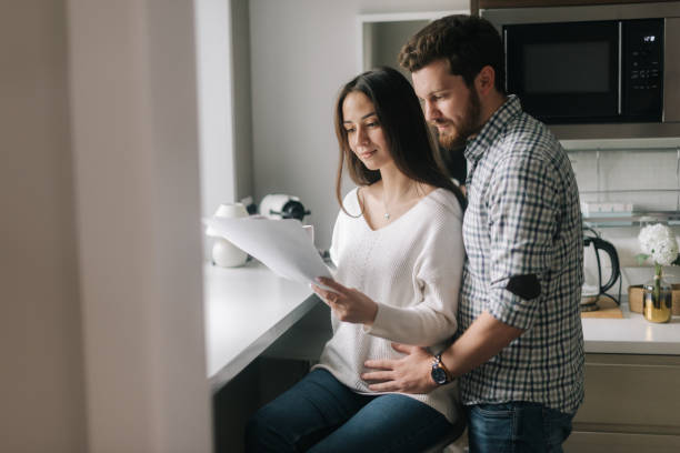 istock Smiling young couple reading documents at home in the kitchen near the window 1190568230