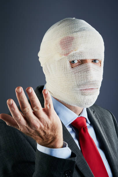 istock Businessman wrapped in bandages looks at camera, shrugging 1190568607