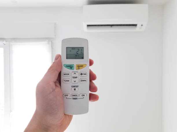 istock Modern air conditioner unit with a hand holding a remote. 1190569391