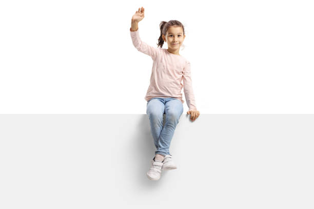 petite fille heureuse s'asseyant sur un panneau et agitant à l'appareil-photo - sitting isolated child beautiful photos et images de collection