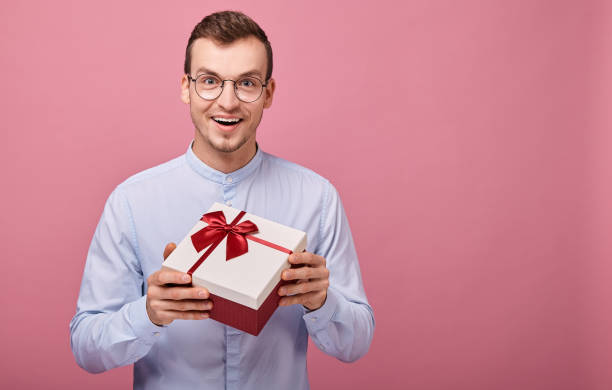 istock Surprised man with black glasses holds a gift in a box 1190572574