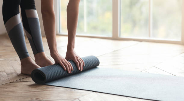 Girl getting ready before morning yoga practice Cropped photo of girl getting ready before morning yoga practice, placing her yoga mat on floor at fitness studio, panorama with copy space mat stock pictures, royalty-free photos & images