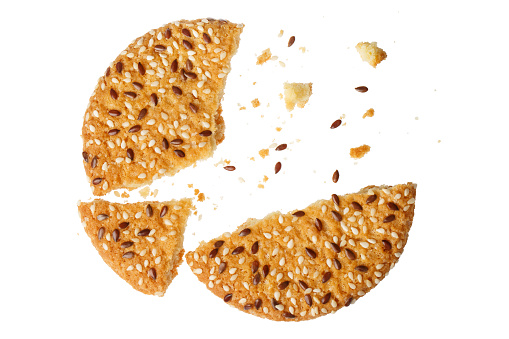 Close-up of oatmeal cookie breaking into pieces, isolated on white background