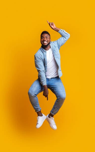 istock Black guy jumping in air, pointing up and down with hands 1190574590