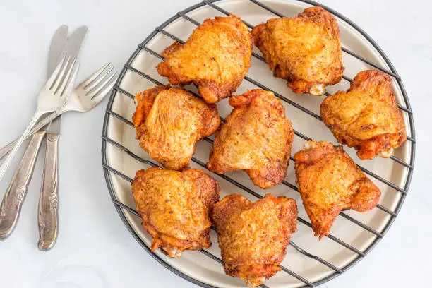 Crispy Oven Fried Chicken Thighs on a grill Rack on White Background, Top View Food Photography.