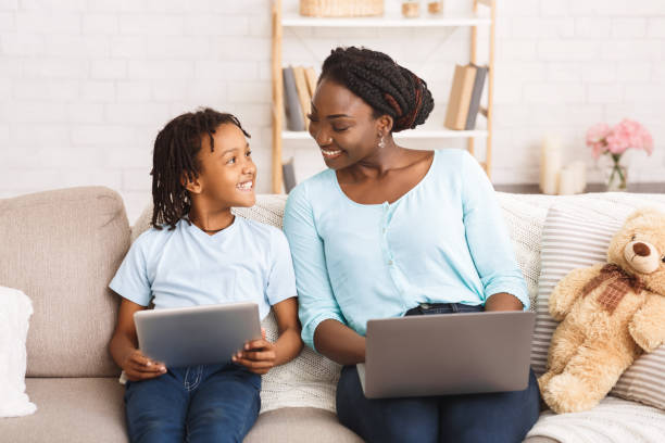 black mom and daughter planning their dream trip - laptop women child digital tablet imagens e fotografias de stock