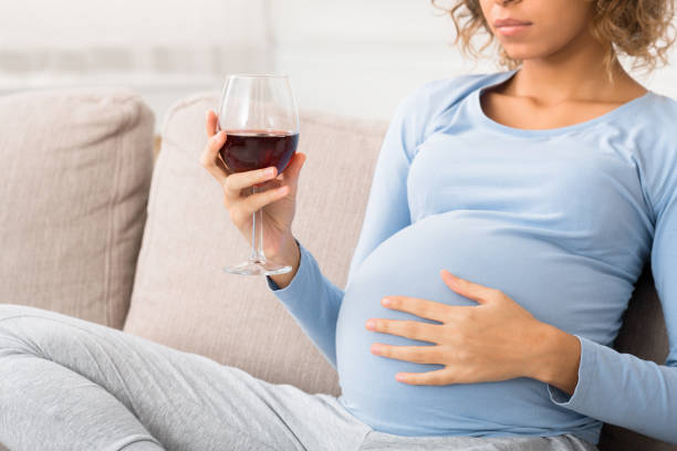 femme expectante irresponsable retenant le verre de vin - abdomen addiction adult alcohol photos et images de collection