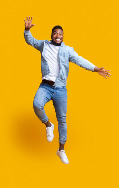 istock Cheerful black guy having fun, jumping in air on yellow background 1190580157