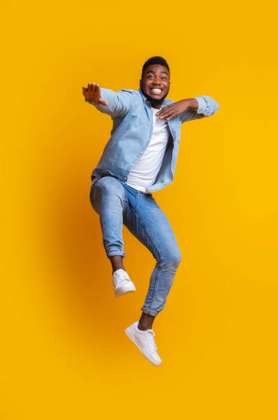 drôle de gars afro sautant et faisant des mouvements de karaté sur le fond jaune - humor men laughing teenager photos et images de collection