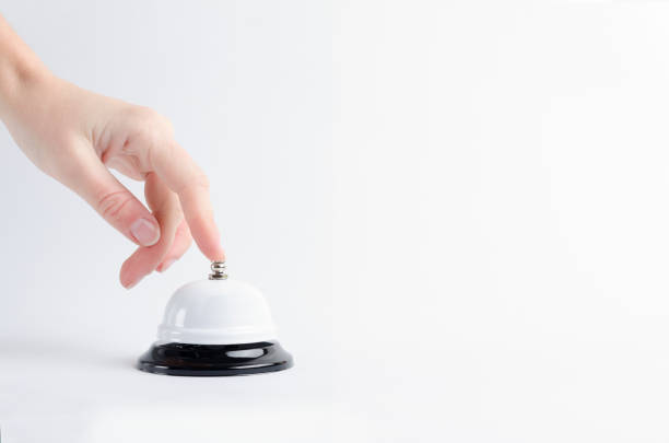 Closeup of female finger on the call bell that standing on the white surface