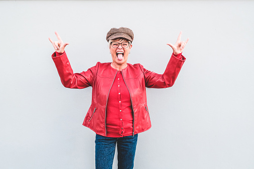 Trendy senior woman dancing rock music wearing fashion clothes - Hipster mature female having fun posing in front of the camera - Joyful elderly lifestyle and feminism concept - Focus on face