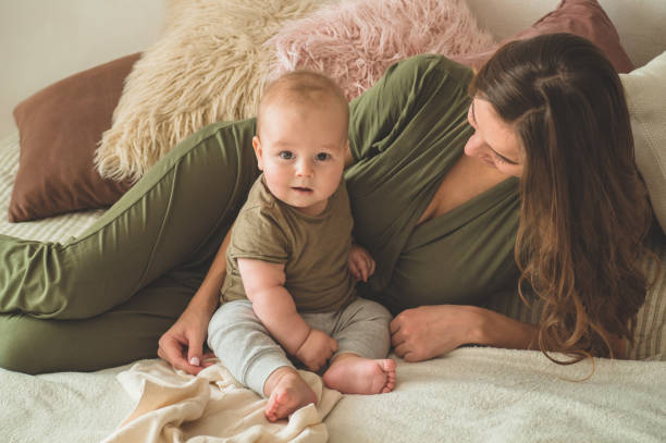 Home portrait of a baby boy with mother on the bed. Mom holding and kissing her child. Home portrait of a baby boy with mother on the bed. Mom holding and kissing her child. Mother day concept cute boy show love symbol hand stock pictures, royalty-free photos & images