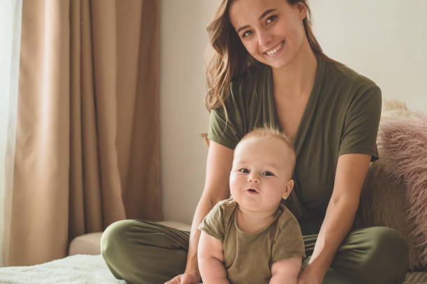 Home portrait of a baby boy with mother on the bed. Mom holding and kissing her child. Home portrait of a baby boy with mother on the bed. Mom holding and kissing her child. Mother day concept cute boy show love symbol hand stock pictures, royalty-free photos & images