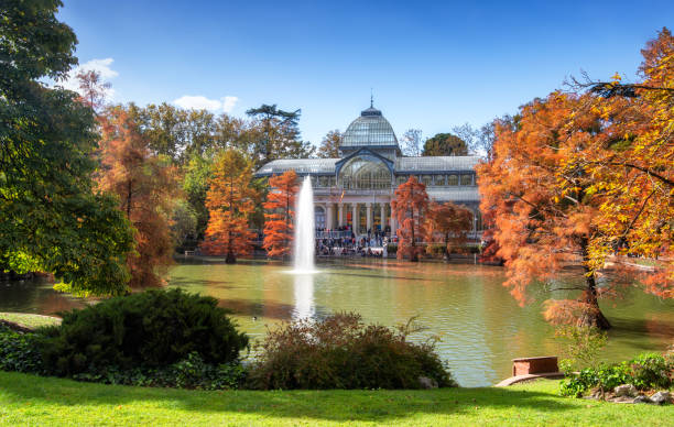crystal palace in Parque del Retiro at autumn, Madrid November 3, 2019 - Madrid, Spain: Tourists and locals gather outside the Crystal Palace (Palacio de Cristal) in the Retiro Park in Madrid at autumn. Designed by architect Ricardo Velázquez Bosco, it was built in 1887 to exhibit flora and fauna from the Philippines palacio de cristal photos stock pictures, royalty-free photos & images