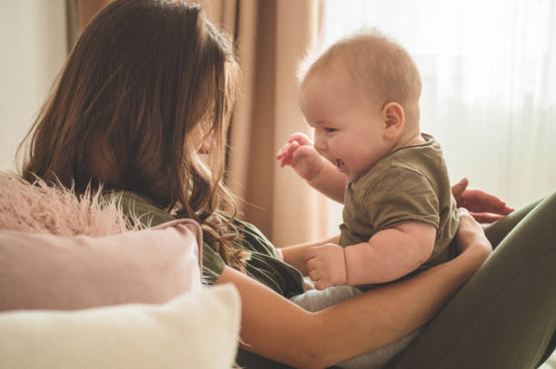 Home portrait of a baby boy with mother on the bed. Mom holding and kissing her child. Home portrait of a baby boy with mother on the bed. Mom holding and kissing her child. Mother day concept cute boy show love symbol hand stock pictures, royalty-free photos & images