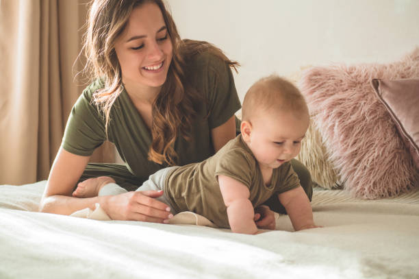 Home portrait of a baby boy with mother on the bed. Mom holding and kissing her child. Home portrait of a baby boy with mother on the bed. Mom holding and kissing her child. Mother day concept cute boy show love symbol hand stock pictures, royalty-free photos & images