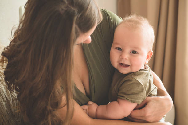 Home portrait of a baby boy with mother on the bed. Mom holding and kissing her child. Home portrait of a baby boy with mother on the bed. Mom holding and kissing her child. Mother day concept cute boy show love symbol hand stock pictures, royalty-free photos & images