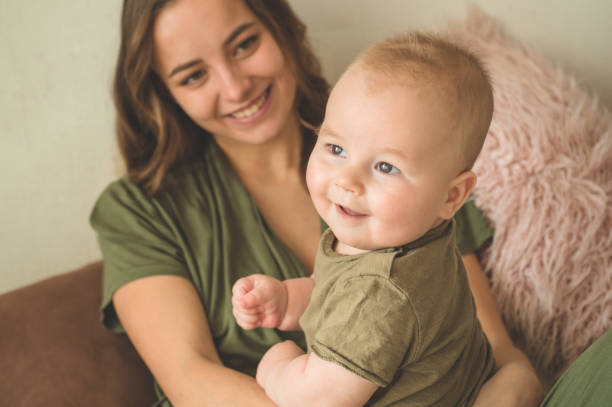 Home portrait of a baby boy with mother on the bed. Mom holding and kissing her child. Home portrait of a baby boy with mother on the bed. Mom holding and kissing her child. Mother day concept cute boy show love symbol hand stock pictures, royalty-free photos & images