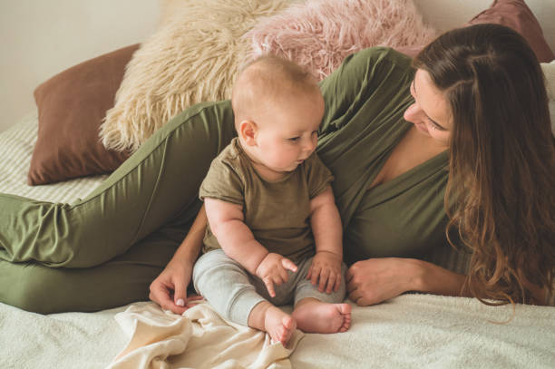 Home portrait of a baby boy with mother on the bed. Mom holding and kissing her child. Home portrait of a baby boy with mother on the bed. Mom holding and kissing her child. Mother day concept cute boy show love symbol hand stock pictures, royalty-free photos & images