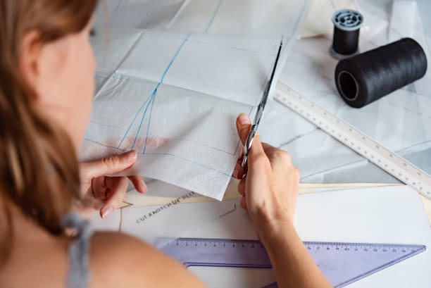 istock Woman tailor during work on sewing patterns, cutting pattern with scissors. Fashion design concept. 1190585942