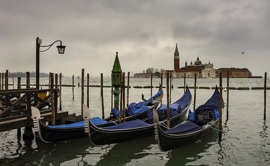 Venice, Italy, April 1, 2016: The gondolas sway on the waves of the Venetian lagoon. In the background the church San Giorgio di Maggiore on die island of the same name.