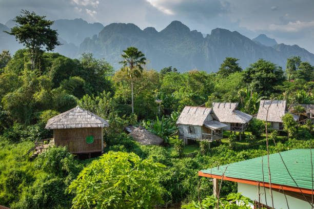 pueblo y montaña en vang vieng, laos - laos hut southeast asia shack fotografías e imágenes de stock