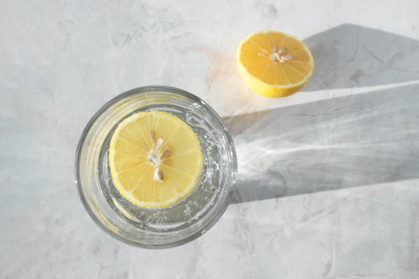 Soda water with slice of lemon in glass on marble table. Detox healthy drink concept, top view stock photo
