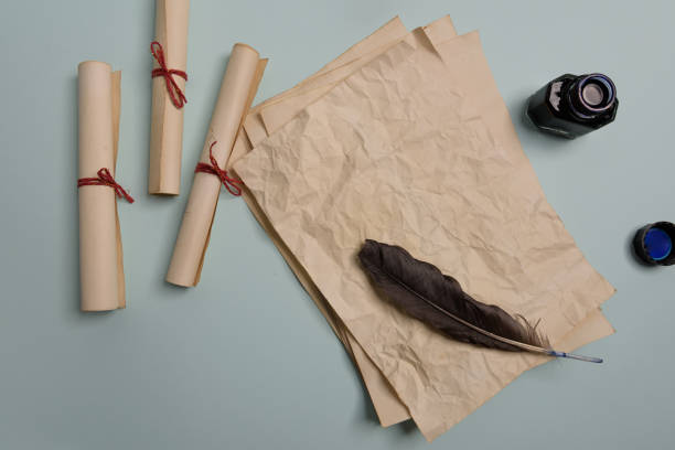 istock Raven feather, inkwell and old yellowed paper on red background. Copy space. 1190593268