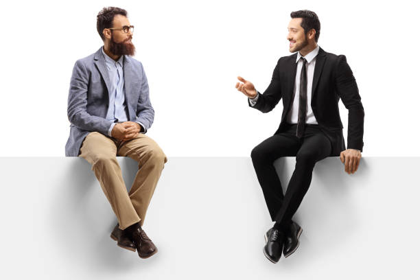 due uomini seduti su un pannello e che hanno una conversazione - sitting foto e immagini stock