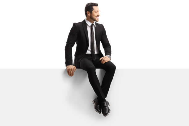 istock Young handsome man in a suit sitting on a panel 1190601402