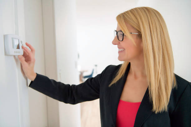 istock A Smiling business Woman Adjusting Thermostat On Home Heating System 1190602489