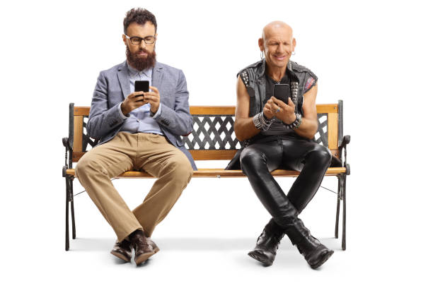 istock Bearded man and a punker sitting on a bench and typing on mobile phones 1190602525