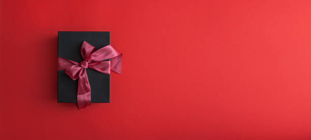 Black gift box wrapped with crimson ribbon stock photo