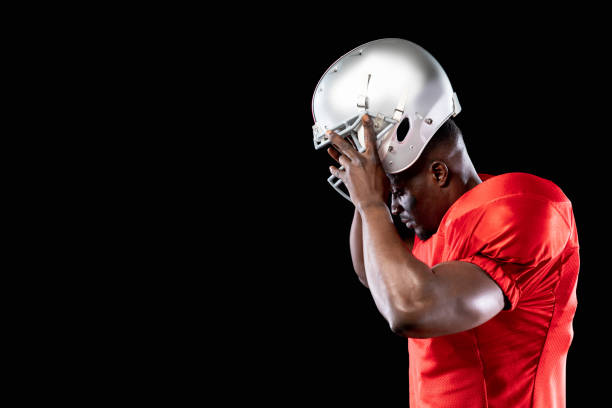 Football player holding ball closely with emotional concentration. Concept of mental strength training, motivation visuals, sport education, team presentations.