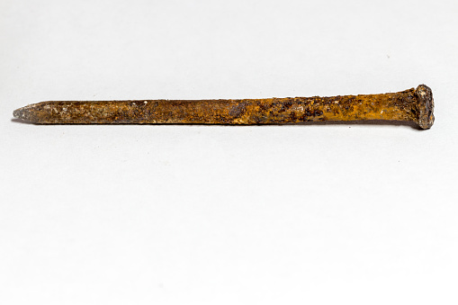 black and white image of a rusty nail covered with a brown oxidant on a white background