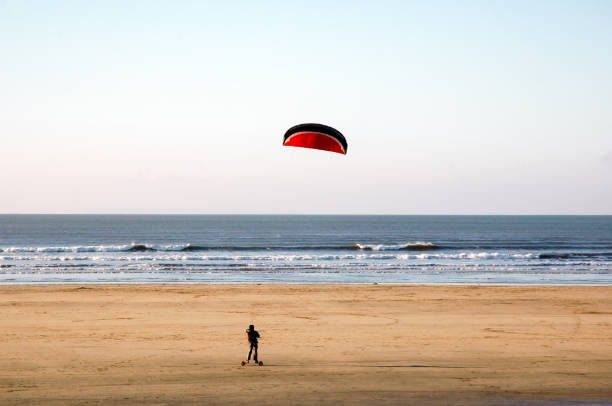 Person riding a kite board or mountain boarding on an empty sandy beach an exciting extreme sport with a kite