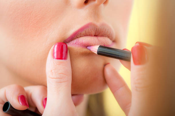 istock Makeup professional artist applying lipstick on lips with pencil 1190622745